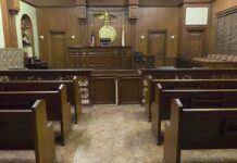 Interior view of an empty courtroom with wooden benches and a judges bench