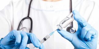 Healthcare worker drawing vaccine from vial with syringe