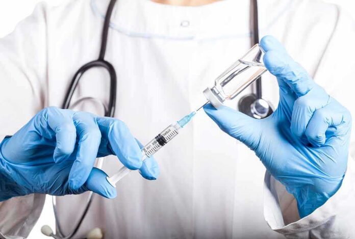 Healthcare worker drawing vaccine from vial with syringe