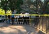 Two Bodies, One Morning — What Happened? Police officers gather behind yellow tape on a tree-lined sidewalk