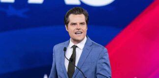man in blue suit speaking at a podium