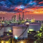 Trump Claims 65B Barrels — Who Really Controls It? Oil refinery with storage tanks at sunset