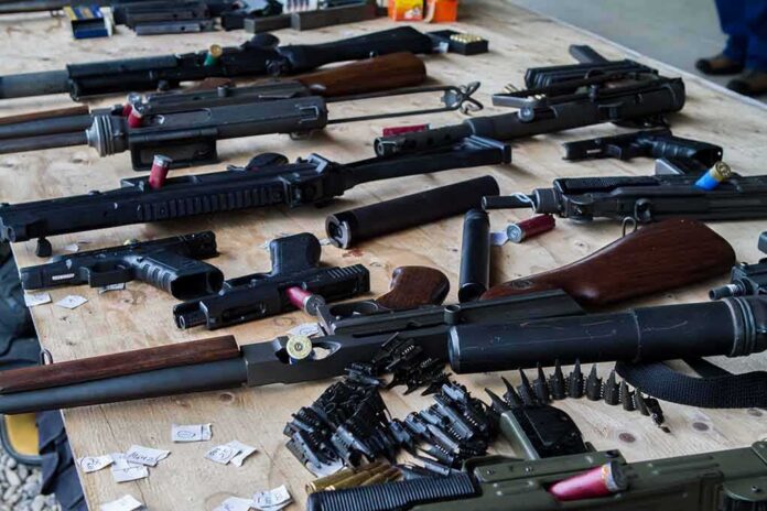 Assorted firearms and ammunition laid out on a wooden table