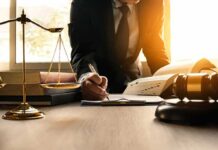Lawyer writing at desk with scales and gavel