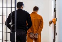 Prisoner in orange jumpsuit handcuffed and escorted by officer