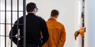 Prisoner in orange jumpsuit handcuffed and escorted by officer