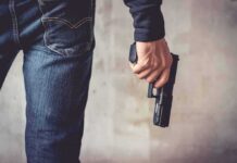 person holding a handgun by their side