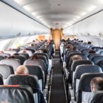 Airplane cabin with passengers seated in rows