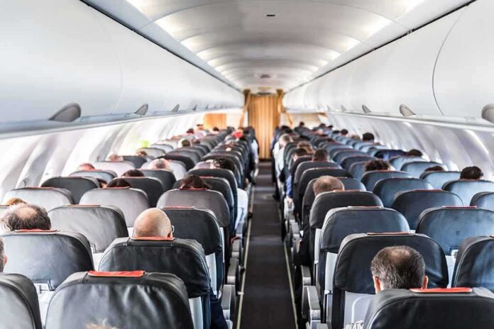 shutterstock_1155913306 Airplane cabin with passengers seated in rows
