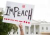 Shock Warning: Trump Targeted Immediately Protester holds an impeach sign in front of a white government building