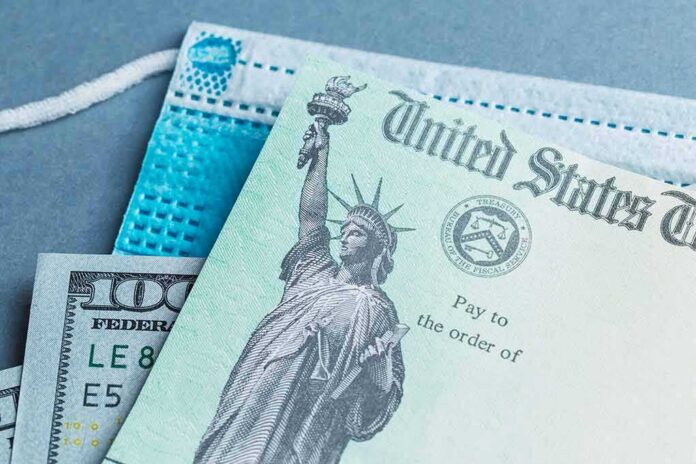 shutterstock_1866625642 U.S. Treasury check with face mask and hundred-dollar bill