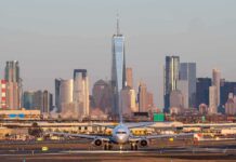 Airplane taxiing on runway with city skyline in background