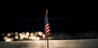 Small American flag on a memorial with bokeh lights at night