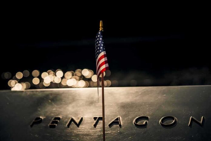 shutterstock_2321355077 Small American flag on a memorial with bokeh lights at night
