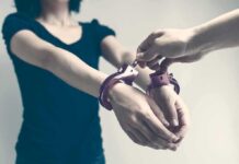 Five-Car Smash Engulfs Candidate Person being handcuffed with hands extended forward