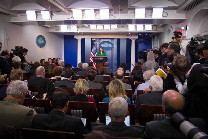 Press secretary at podium addressing reporters in briefing room