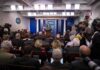 Press Ban Bombshell – Legal Fight Looms Press secretary at podium addressing reporters in briefing room