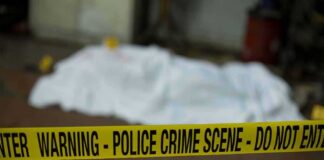 crime scene tape in foreground with covered body in background