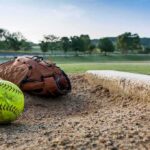 Youth Game Brawl Leaves Dad With Skull Fracture Softball and glove near a base on a dirt field
