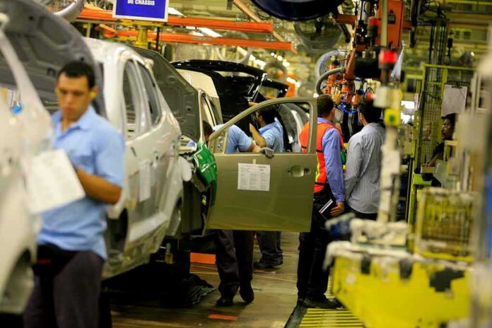 Teddy Williams on an automotive assembly line with workers fitting car doors