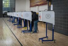 Same-Name Gambit Explodes In Alaska Voters at polling booths in a gymnasium