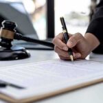 Texas Targets ChatGPT – Kids Locked Out? Hand signing legal document beside gavel and laptop
